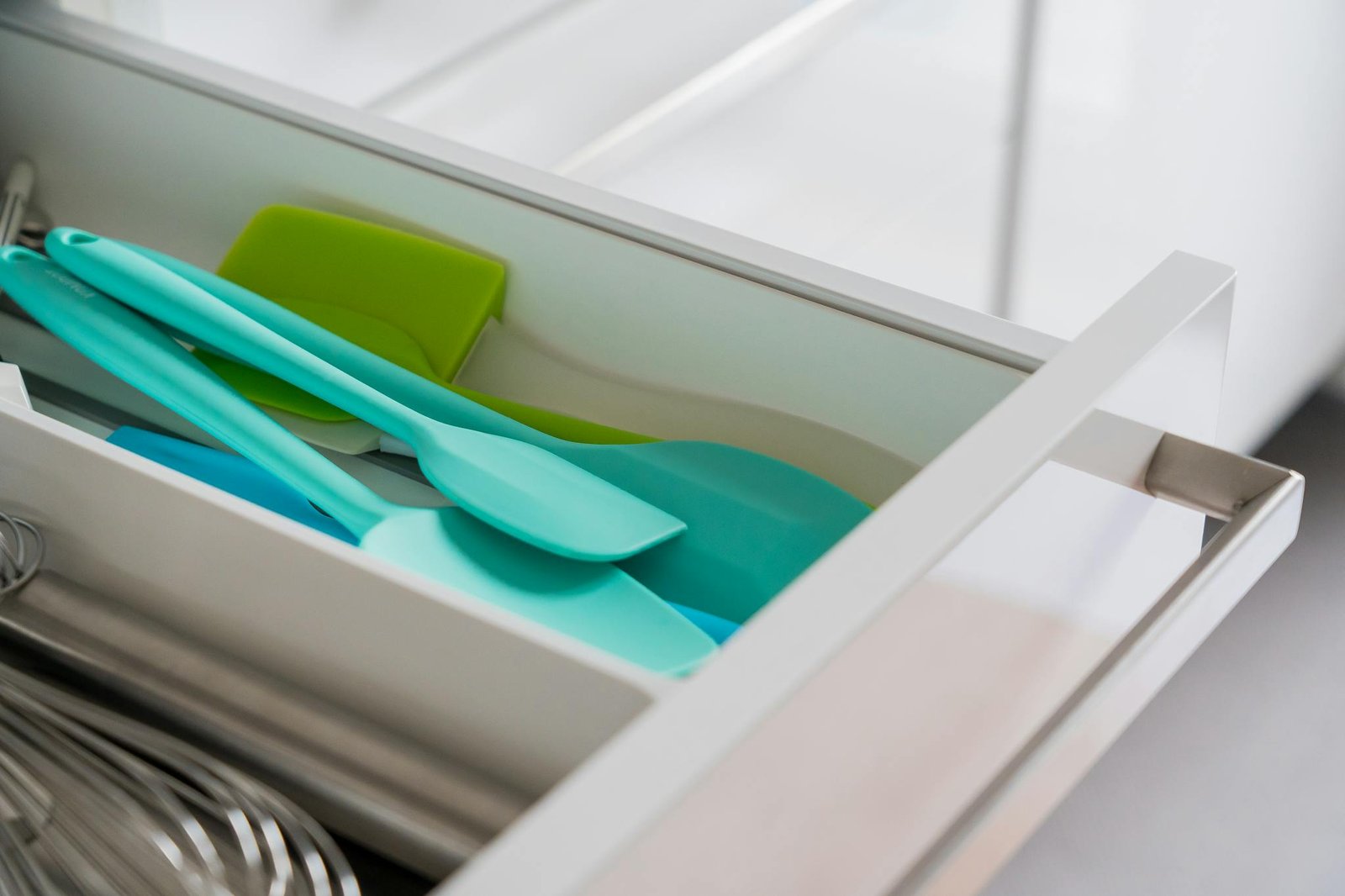 A tidy kitchen drawer featuring organized silicone spatulas and a whisk.