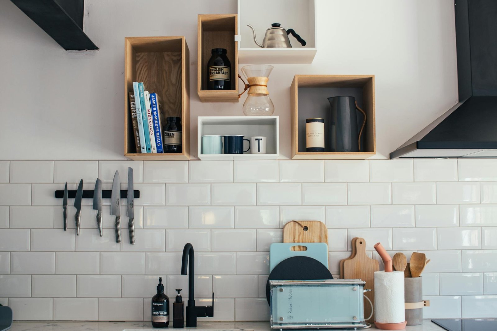 Elegant kitchen setup featuring knives, shelves, and ceramic cookware.