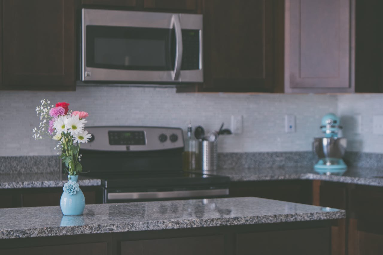 A contemporary kitchen featuring granite countertops and a vase of colorful flowers, creating a warm ambiance.