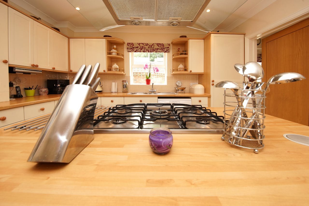 A bright and modern kitchen interior featuring a gas stove, knife block, and cutlery holder on a wooden countertop.